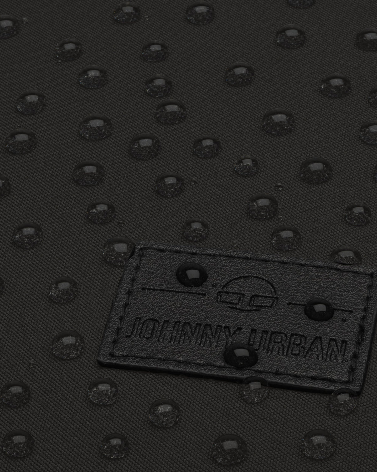 Nahaufnahme des wasserabweisenden schwarzen Stoffes des Rucksacks 'Jona Medium' mit sichtbaren Wassertropfen