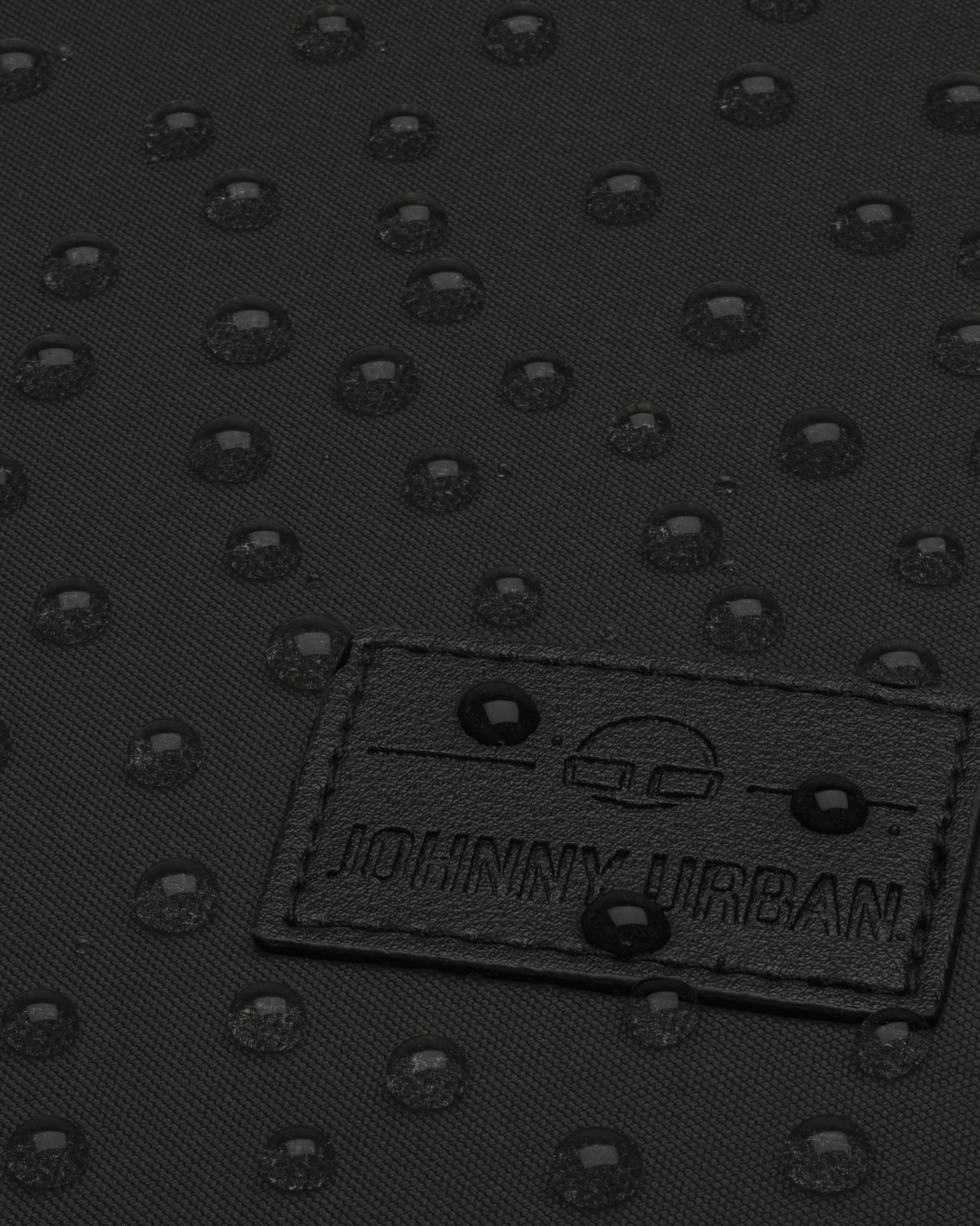 Nahaufnahme des wasserabweisenden schwarzen Stoffes des Rucksacks 'Jona Medium' mit sichtbaren Wassertropfen