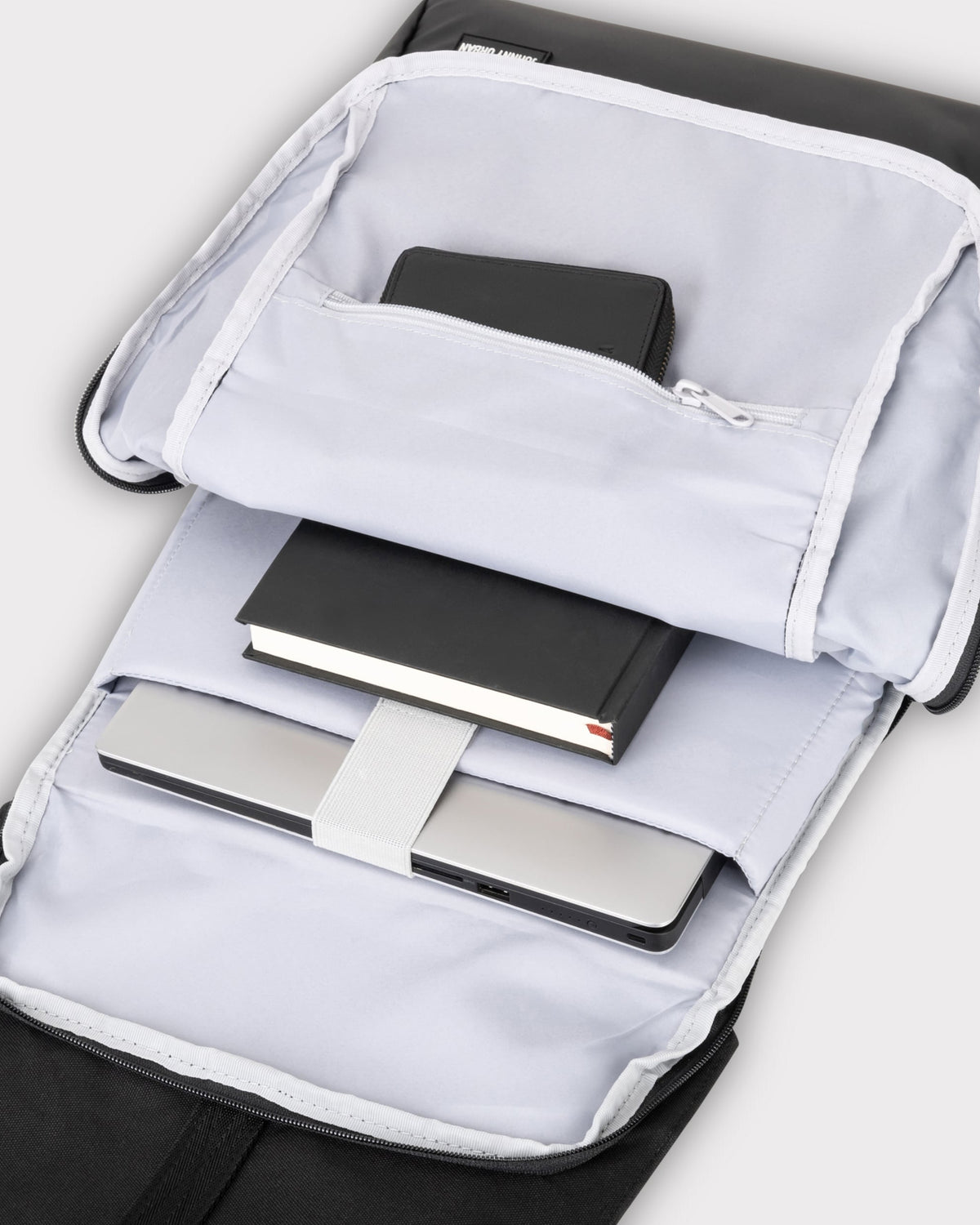Geöffneter schwarzer Johnny Urban Rucksack Mika mit Laptop und Notizbuch im Innenfach