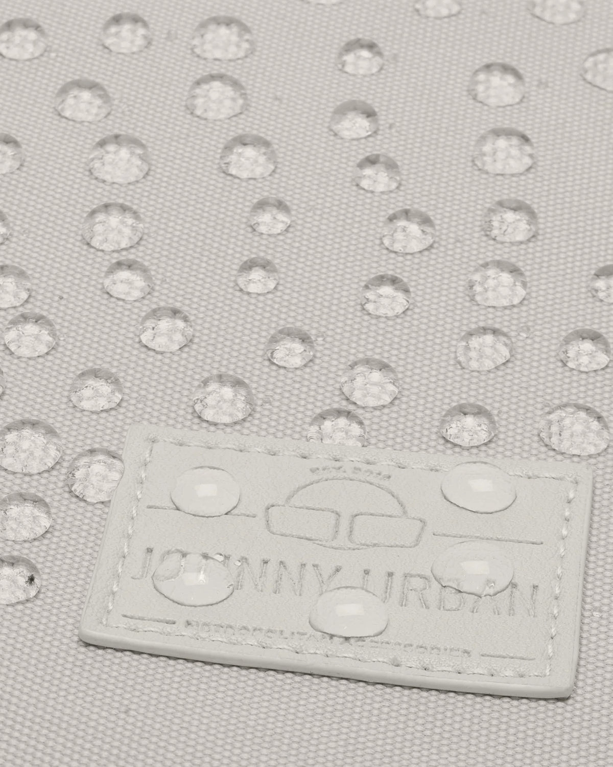 Beige wasserabweisendes Material mit Regentropfen und Johnny Urban Logo auf Tasche