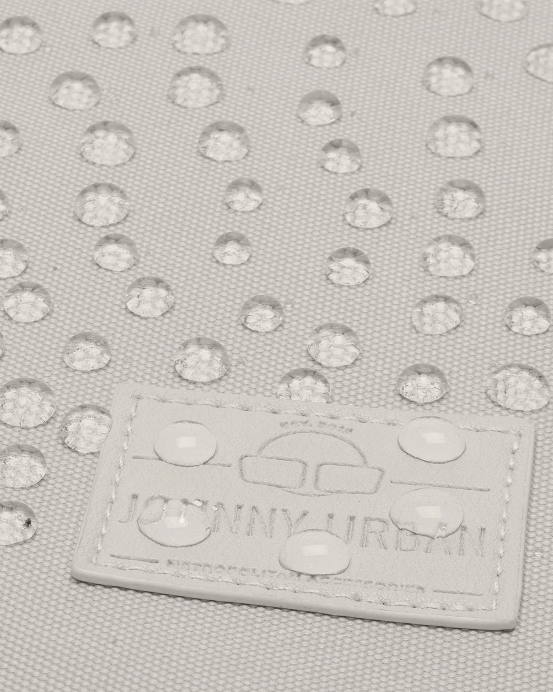 Beige wasserabweisendes Material mit Regentropfen und Johnny Urban Logo auf Tasche