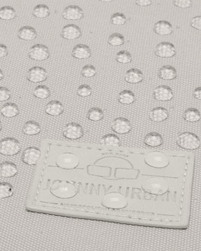 Beige wasserabweisendes Material mit Regentropfen und Johnny Urban Logo auf Tasche