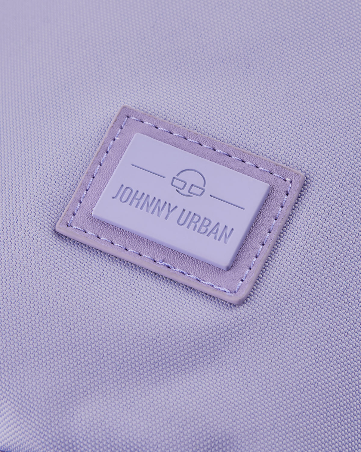 Nahaufnahme des Johnny Urban Logos auf violettem nachhaltigem Stoff der Umhängetasche 'Rue'